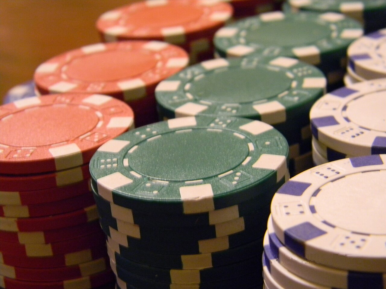 Primer plano de pilas de fichas de casino verdes, rojas y blancas.